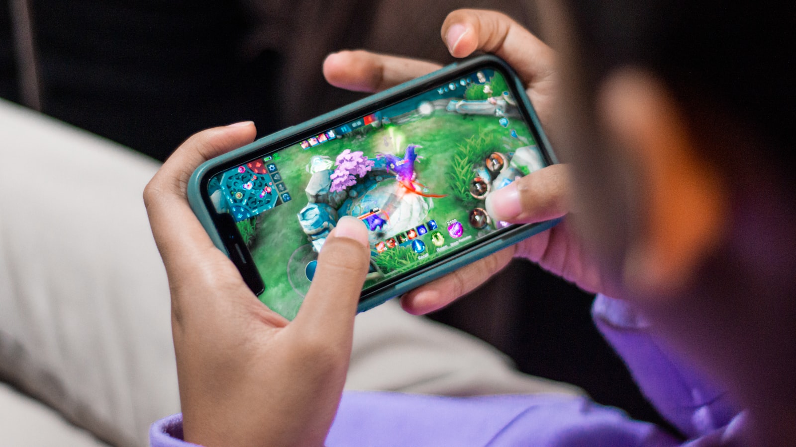 A person's hands holding a phone mid-game, playing a mobile action game