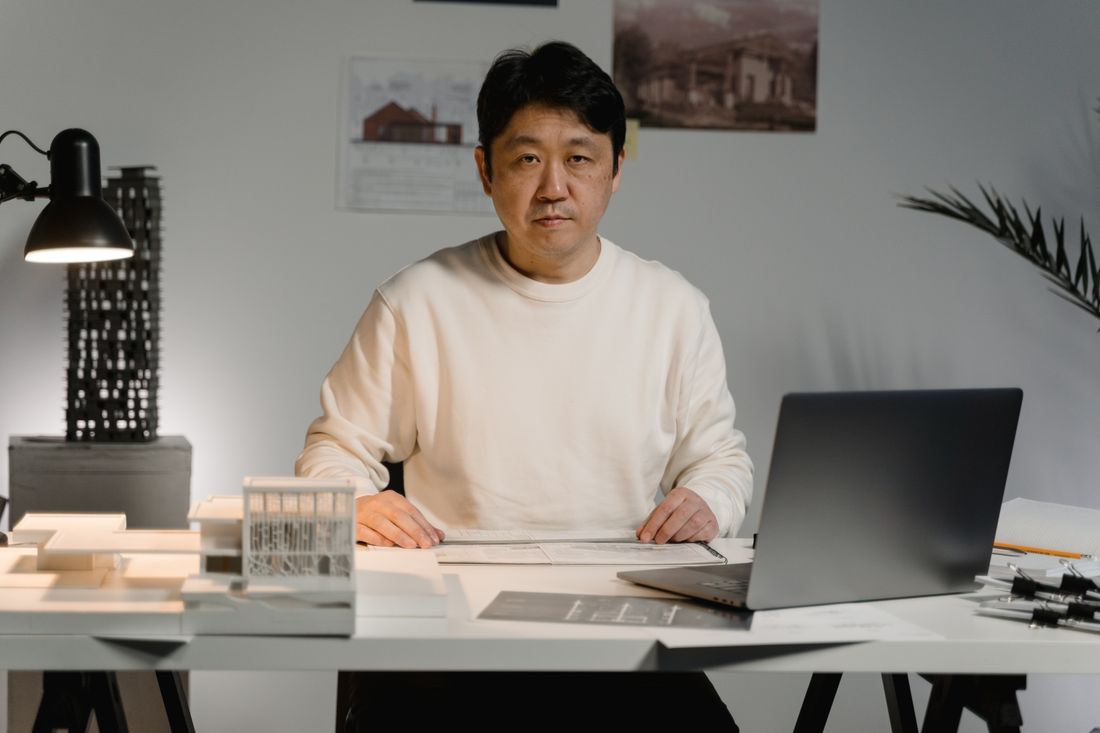 Chidi Okonma at his desk with a scale model and drawings.