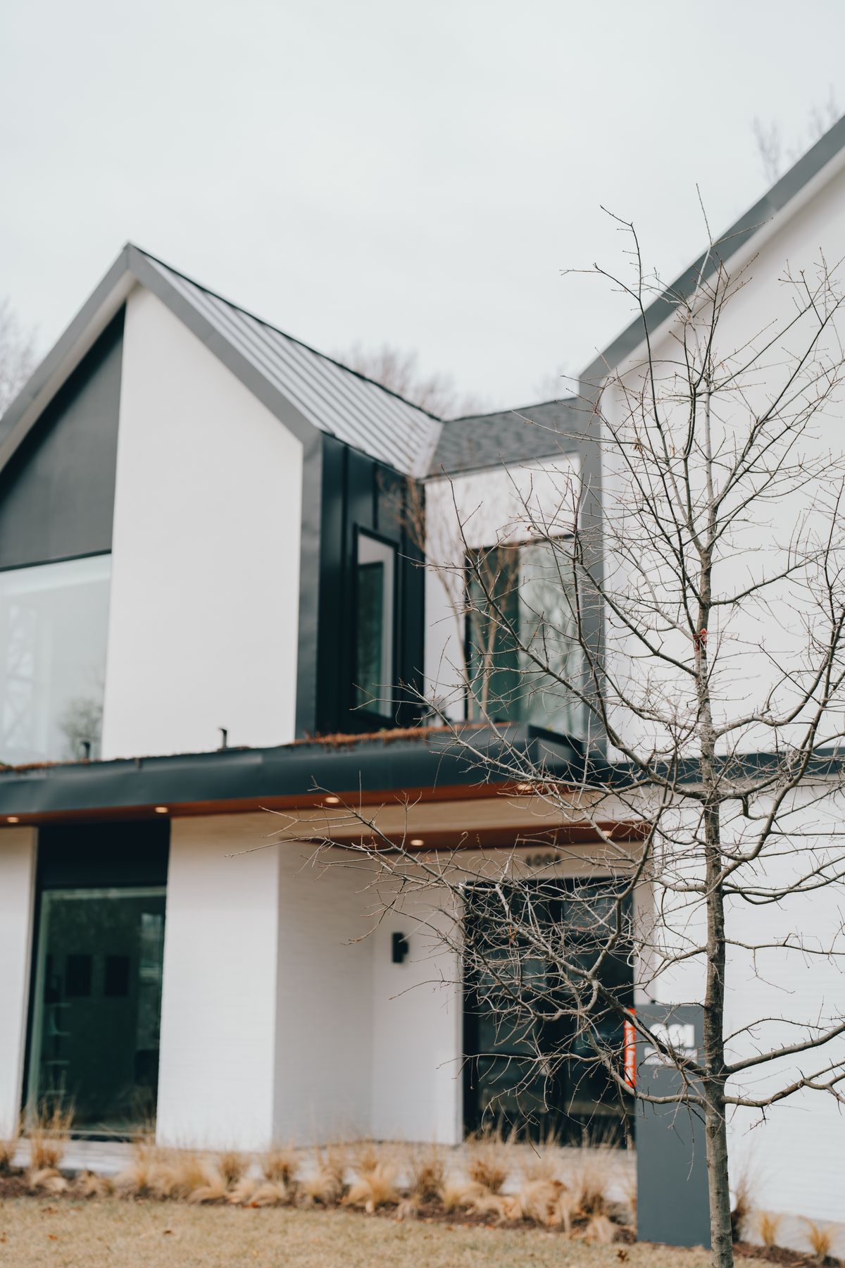A modern gabled house with dark cladding and a covered entrance.