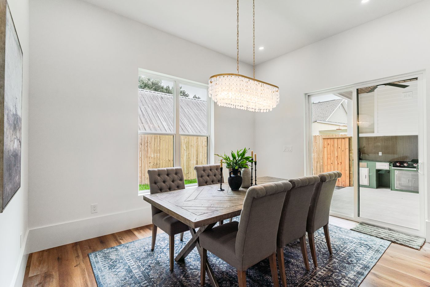 A staged dining room with an upholstered set, a chandelier and a patterned rug.