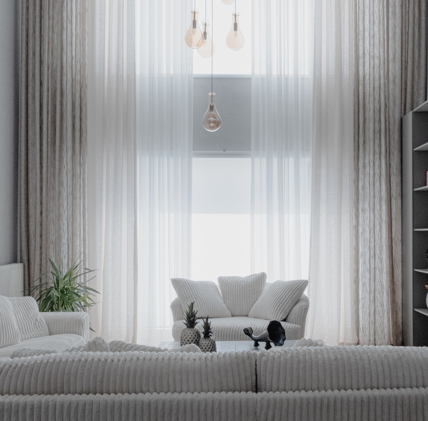 A bright sitting room in cream and stone with full-height sheer curtains.