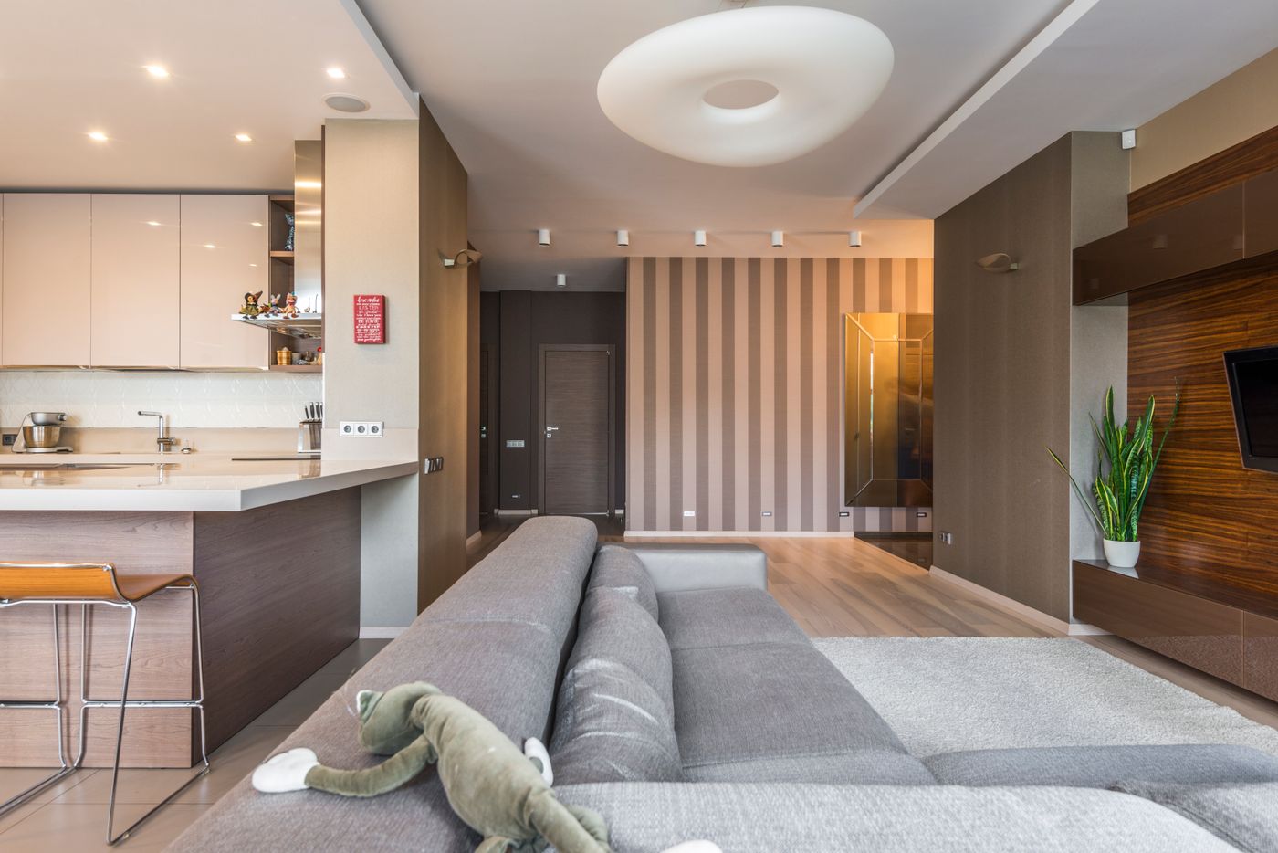 A compact open-plan kitchen and living space in warm timber and stone.