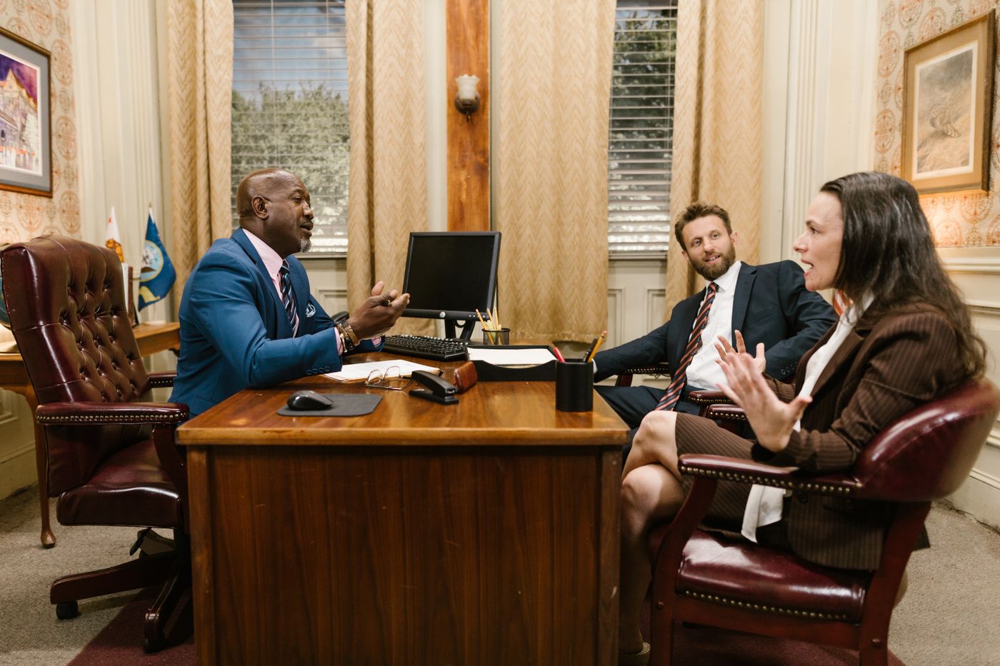 Three solicitors in discussion across a desk in a traditional office.