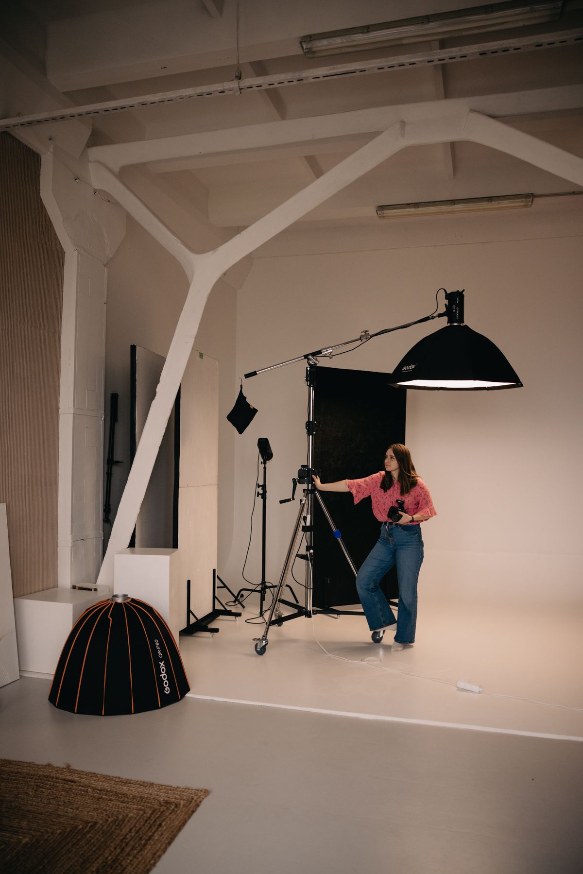 A photographer positioning a boom light in the studio.