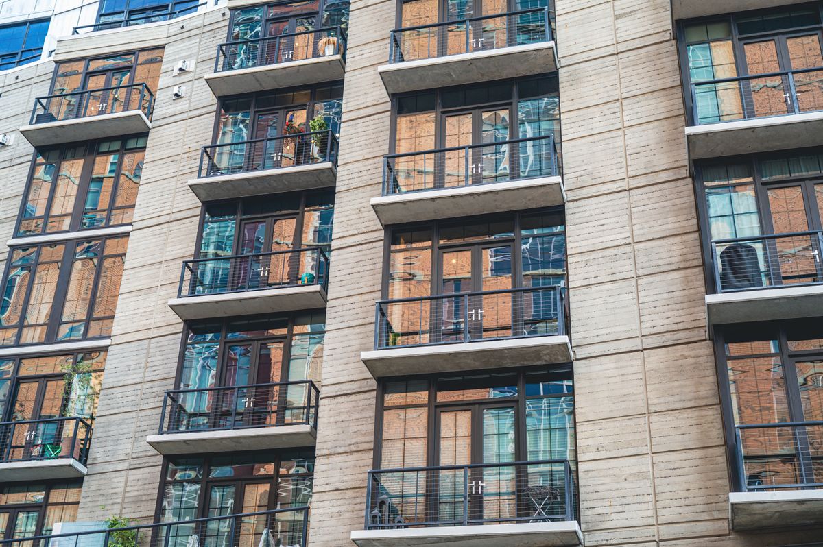 A modern apartment building with concrete facade and glass balconies.