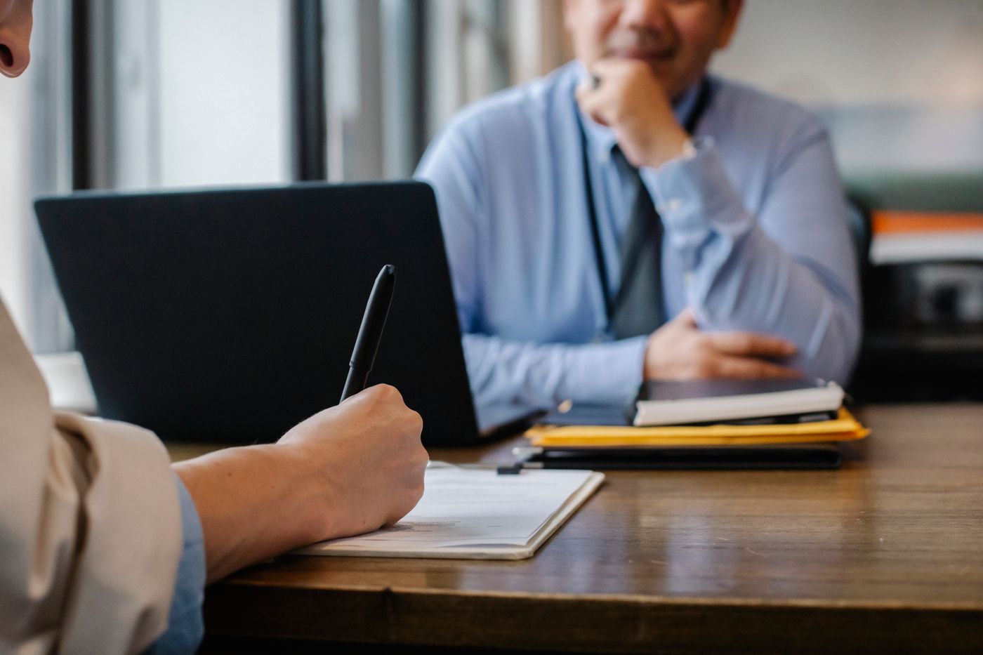 Two people going through paperwork across a table at a signing meeting.