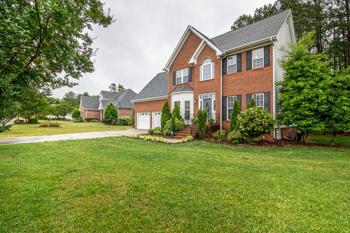 A red brick colonial house set back behind a wide lawn.