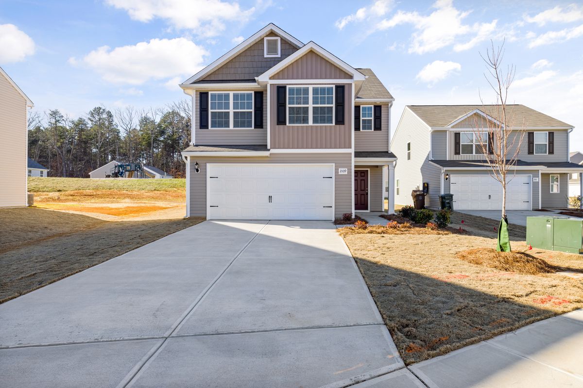 A newly built house with a two-car garage on a young street.