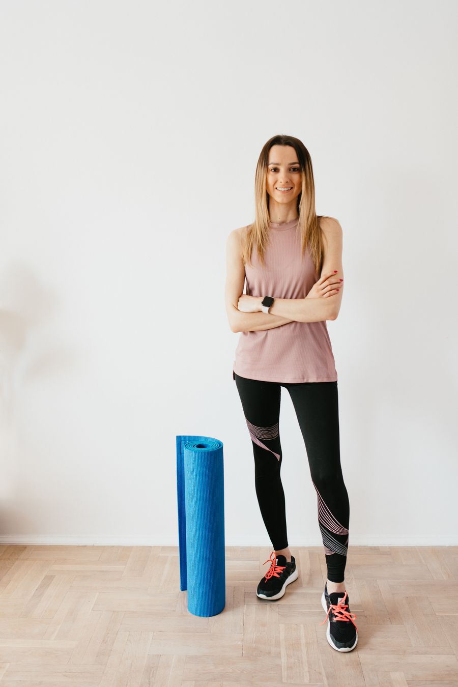 Portrait of Marit Halden standing beside a rolled yoga mat.